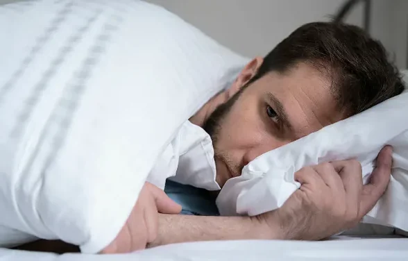 Mann im Bett liegend, die Augen offen, den Kopf auf dem Kissen